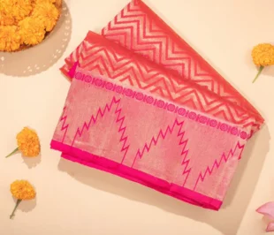 Beautiful cotton saree in pink with intricate floral design along with flowers aside captured adorably by photographer.