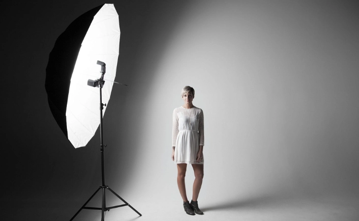 Female model in a white dress posing under studio lighting during a lifestyle photoshoot