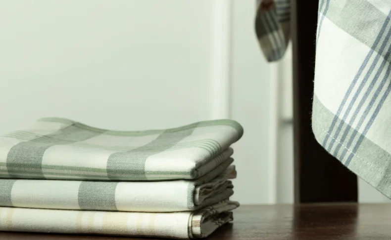 A stack of towels, featuring a white & green plaid pattern, arranged on top of each other perfectly captured in photos.